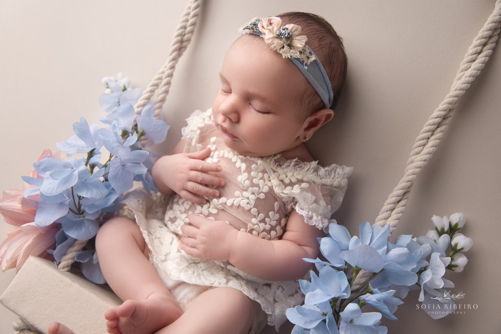 a closeup of a baby girl on a swing prop during a newborn photo session in bernards, nj