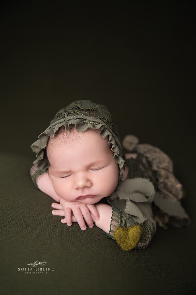 baby girl is posed on olive green with a matching felted heart