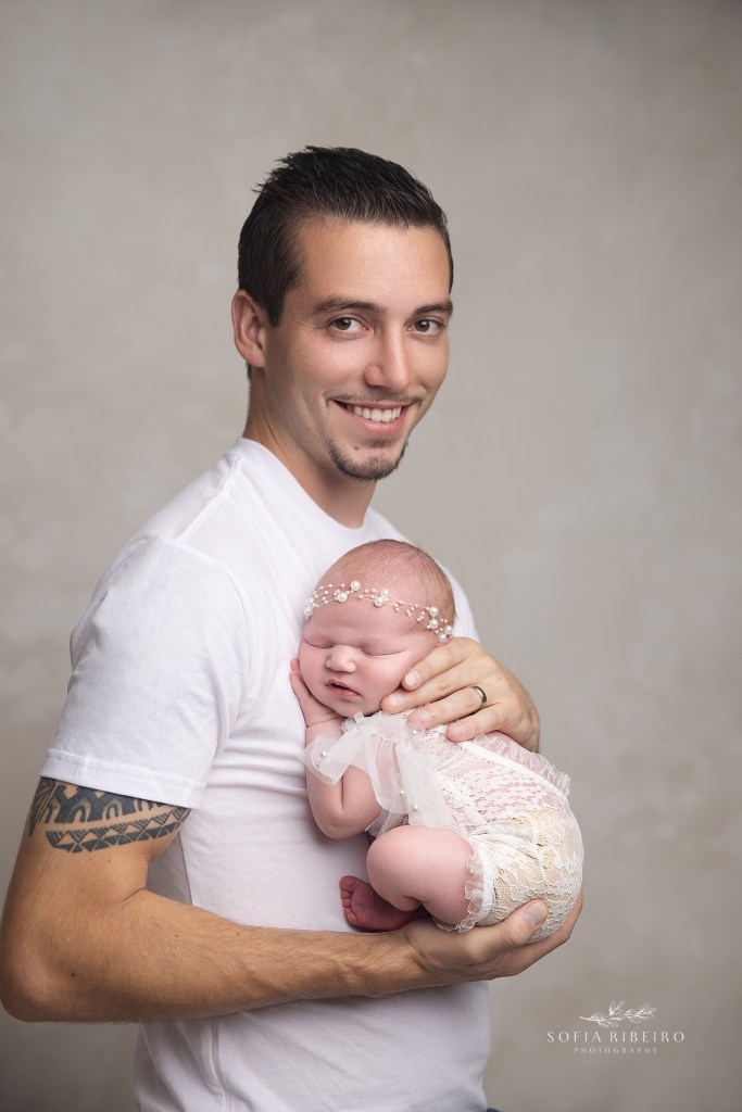 dad proudly holds his new chunky baby girl during newborn phtoos