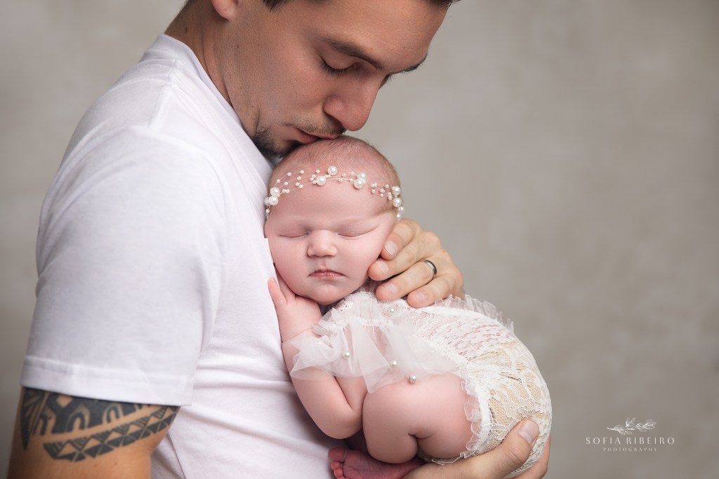 dad kisses his new baby girl on the top of head during newborn photos