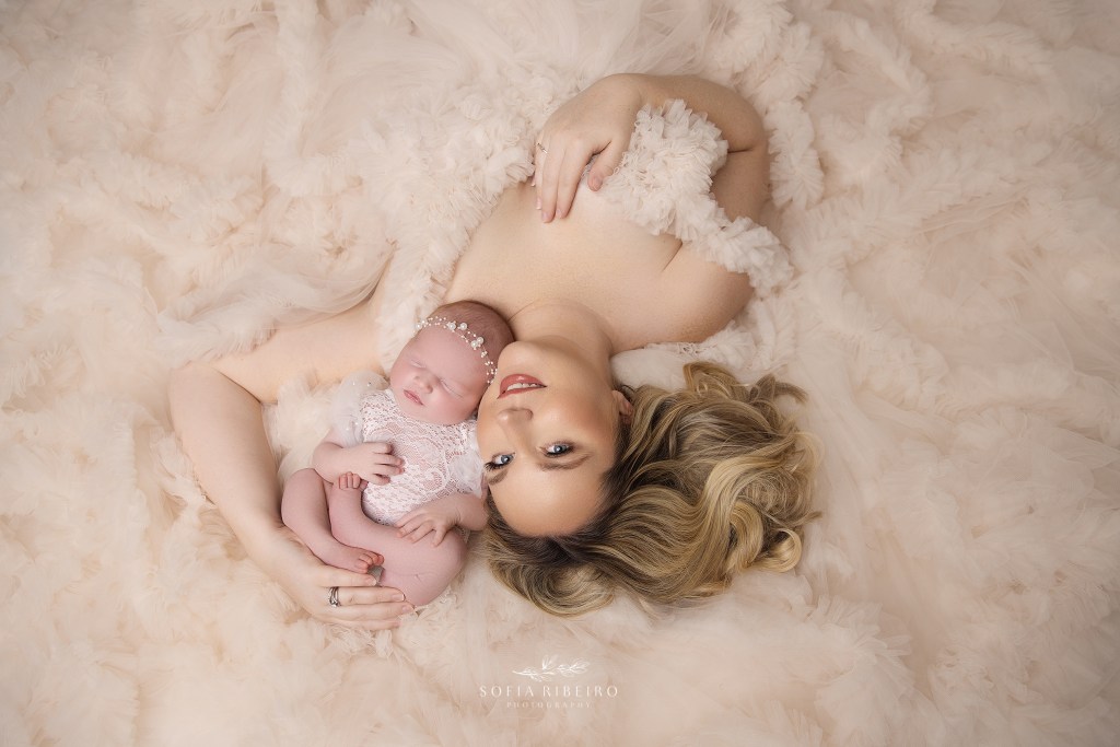 mom lays on the floor in a bed of ruffles with her sweet baby girl sleeping in her arms