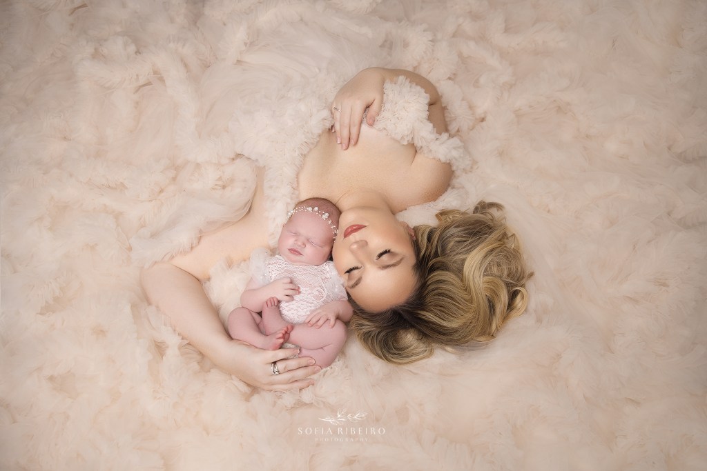 mom lays on the floor in a bed of ruffles with her sweet baby girl sleeping in her arms