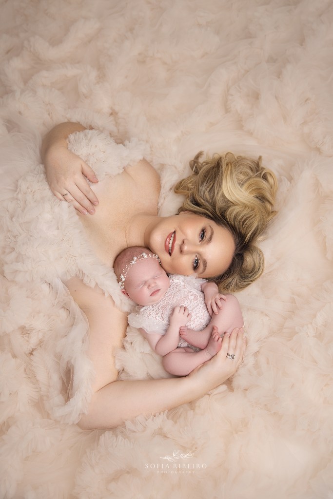 mom lays on the floor in a bed of ruffles with her sweet baby girl sleeping in her arms