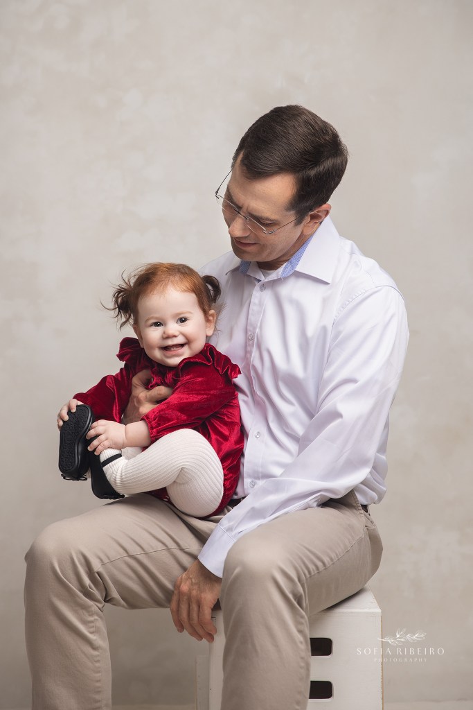 a one year old baby girl giggles vivaciously on daddy's lap for a photo