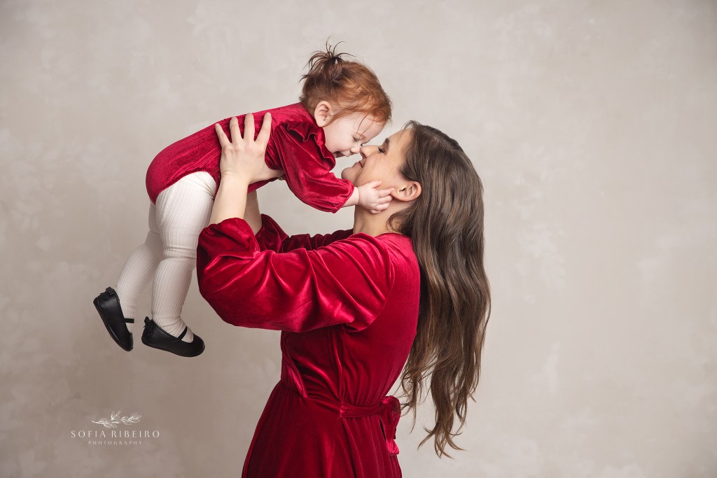 mom snuggles her one year old in matching red velvet looks