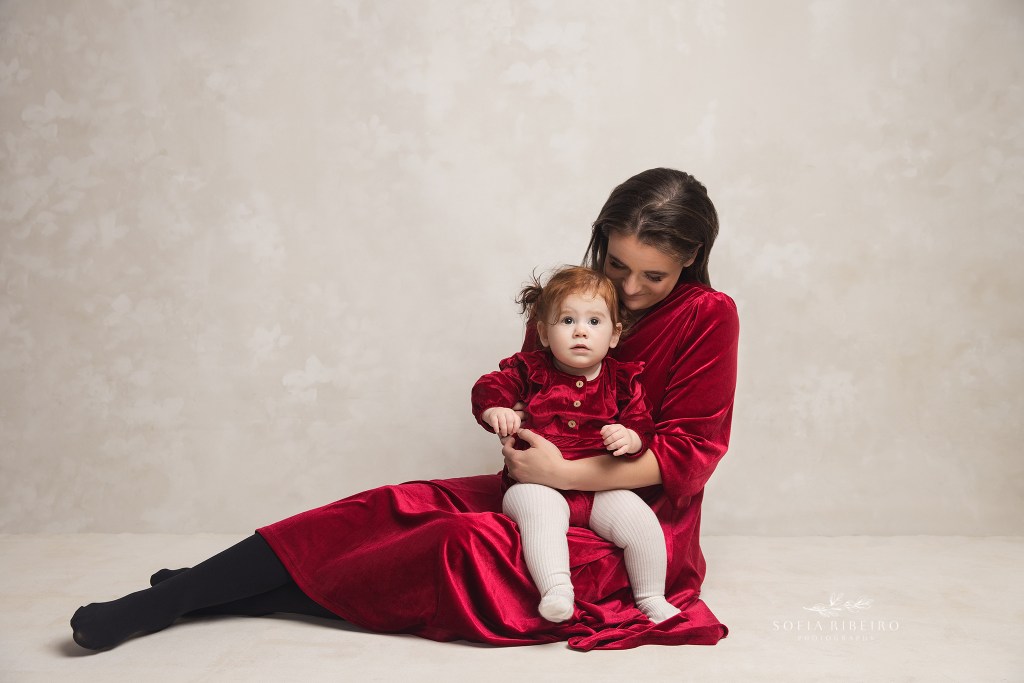 mom snuggles her 1 yr old daughter in matching velvet dresses