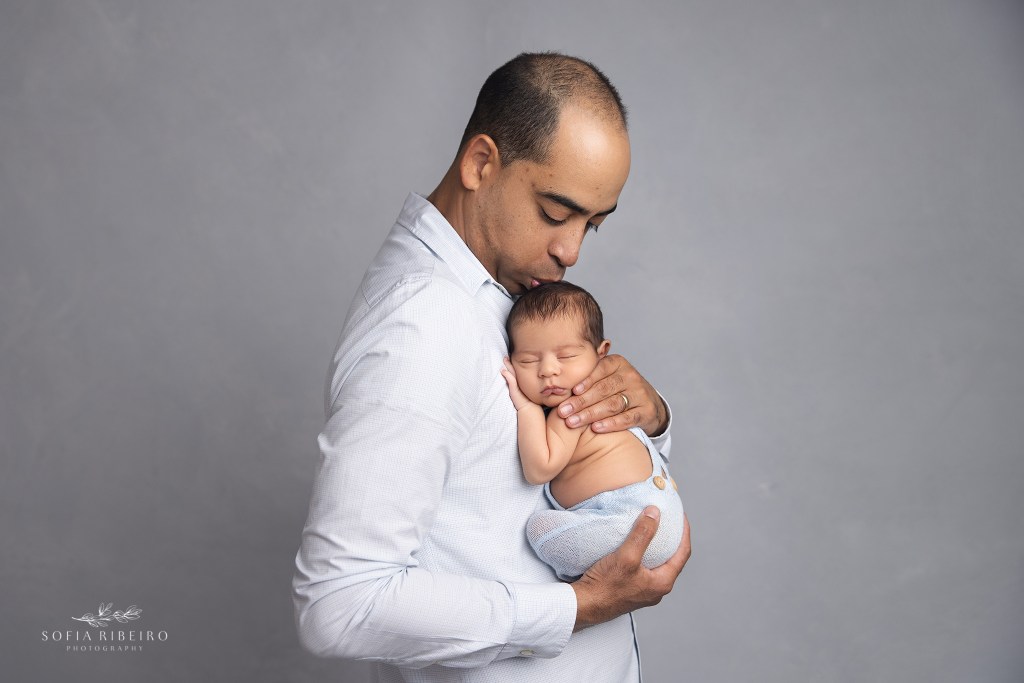 dad gives his new baby boy a kiss on the forehead