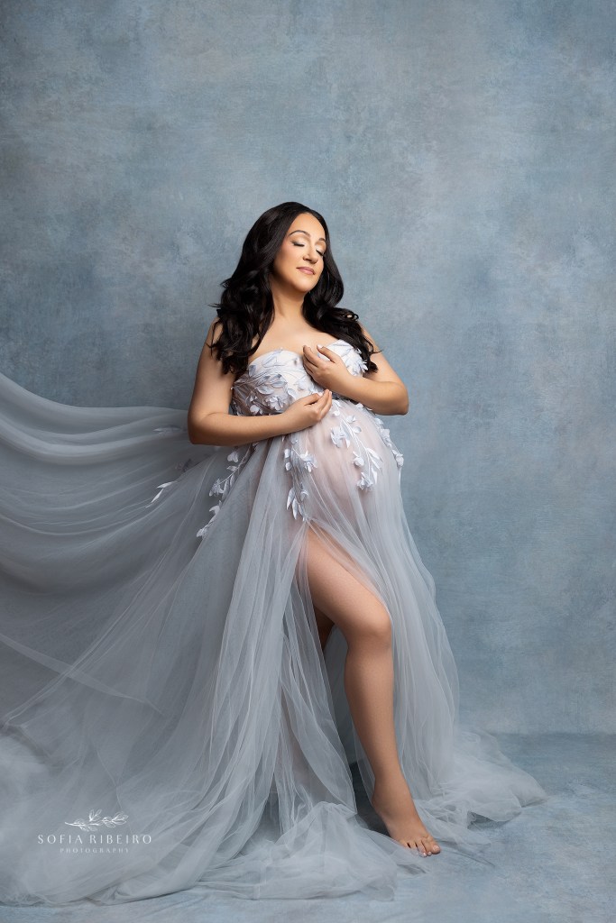 an expectant mom looks ethereal in an embroidered pale blue gown highlighting her baby bump