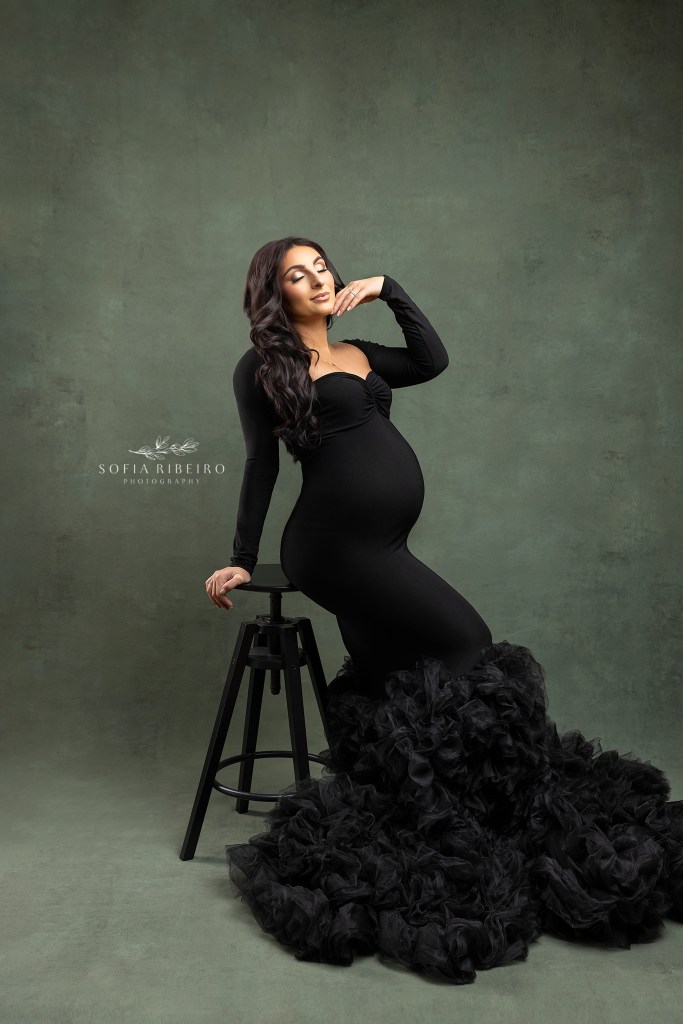 colonia nj maternity photographer poses a mom in an elegant black form fitting gown to create a stunning portrait