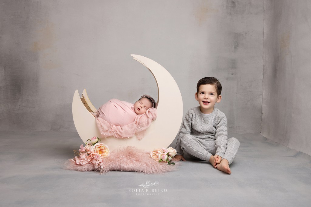 big brother poses with his newborn baby sister in a moon prop in hanover nj newborn photo studio