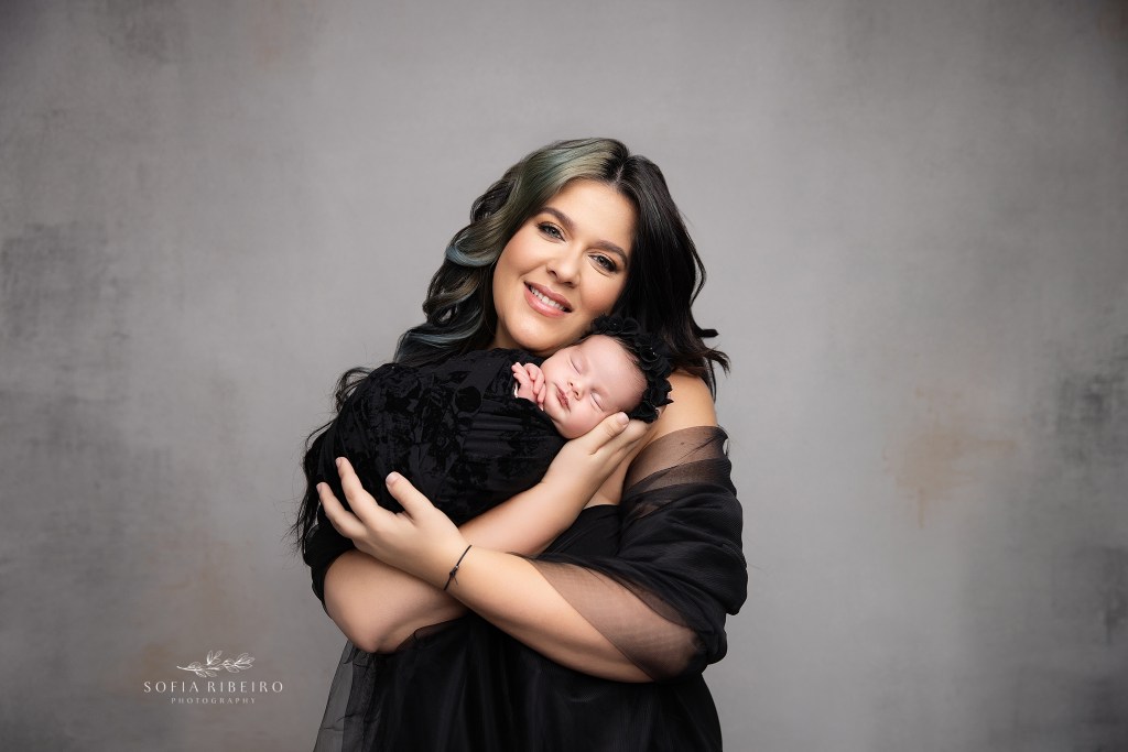 mom beams proudly holding her wrapped baby newborn girl for a portrait