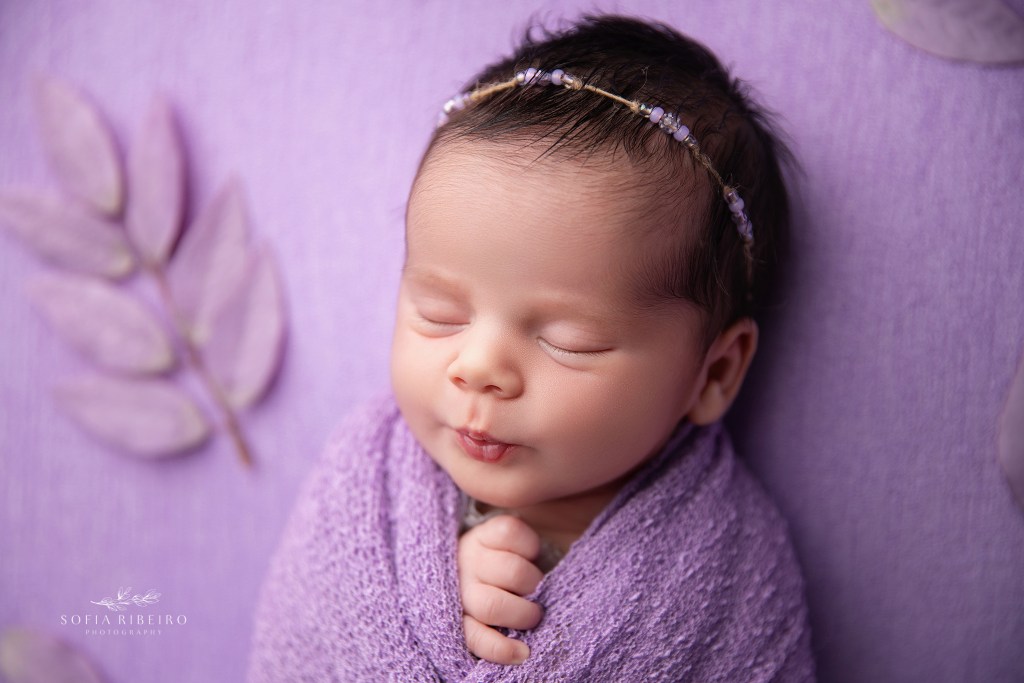 baby girl is wrapped in a lavender wrap for newborn photos
