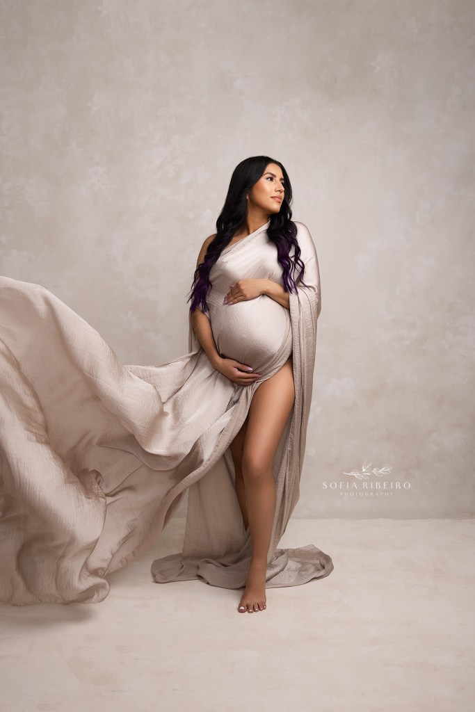 a pregnant mom looks serene with draped flowing fabric highlighting her baby bump at an nj photo studio