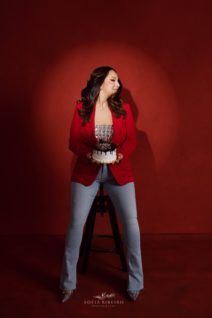 woman poses in a red outfit and a birthday cake to celebrate her 30th birthday with photos
