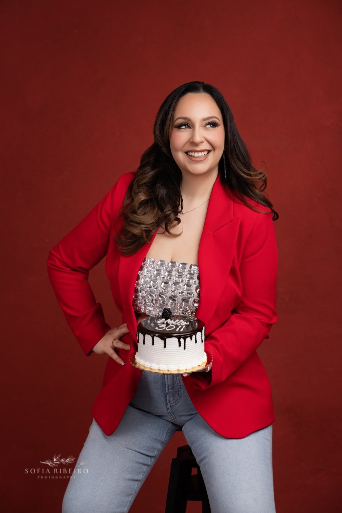 woman poses in a red outfit and a birthday cake to celebrate her 30th birthday with photos