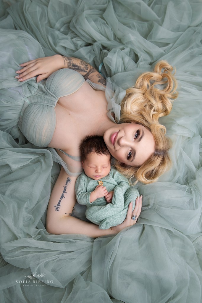 mom snuggles baby in matching sage green looks for newborn photos