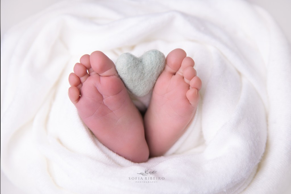 closeup of baby feet holding a felted heart