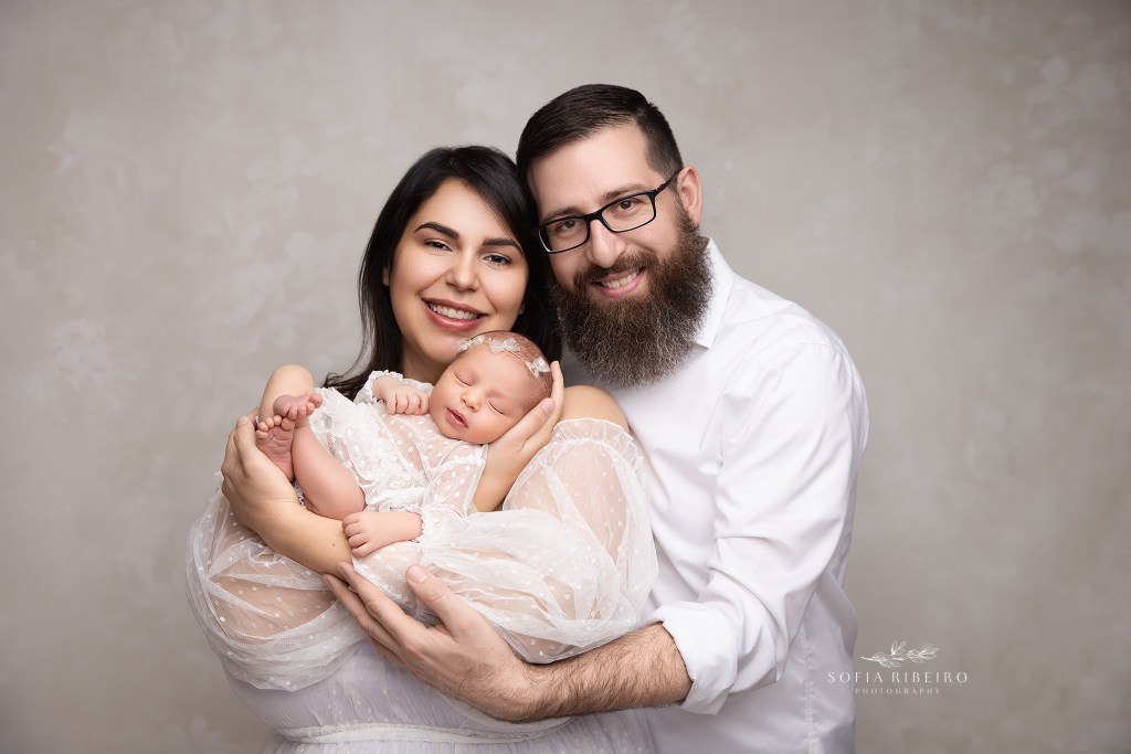 mom and dad smile proudly with their new baby in their arms