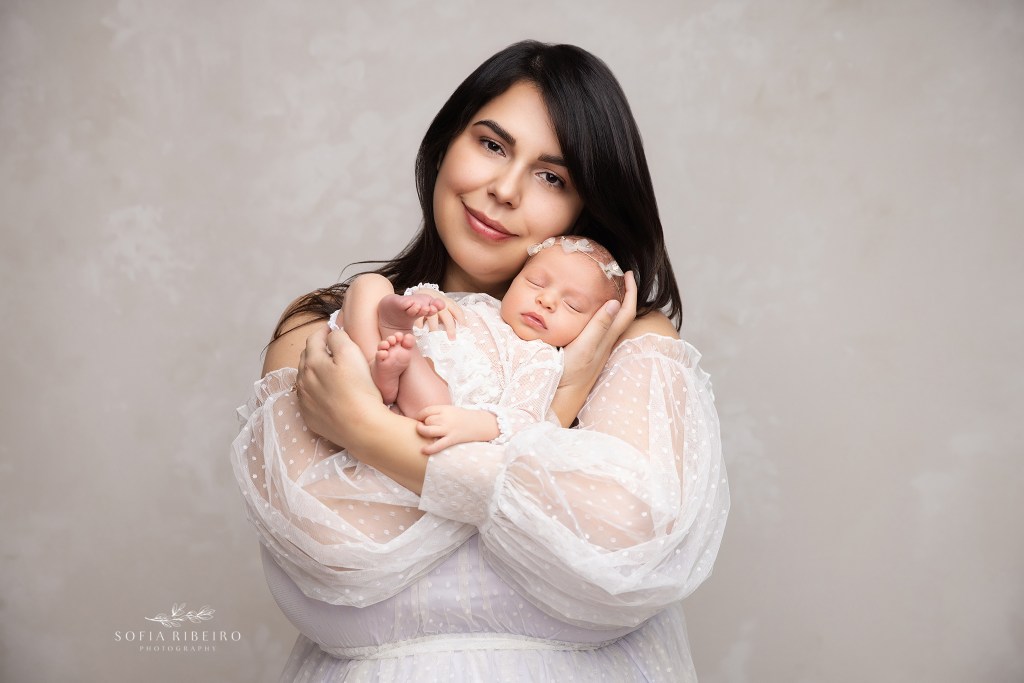 mom cradles her newest baby girl in her arms for newborn protraits in a photo studio