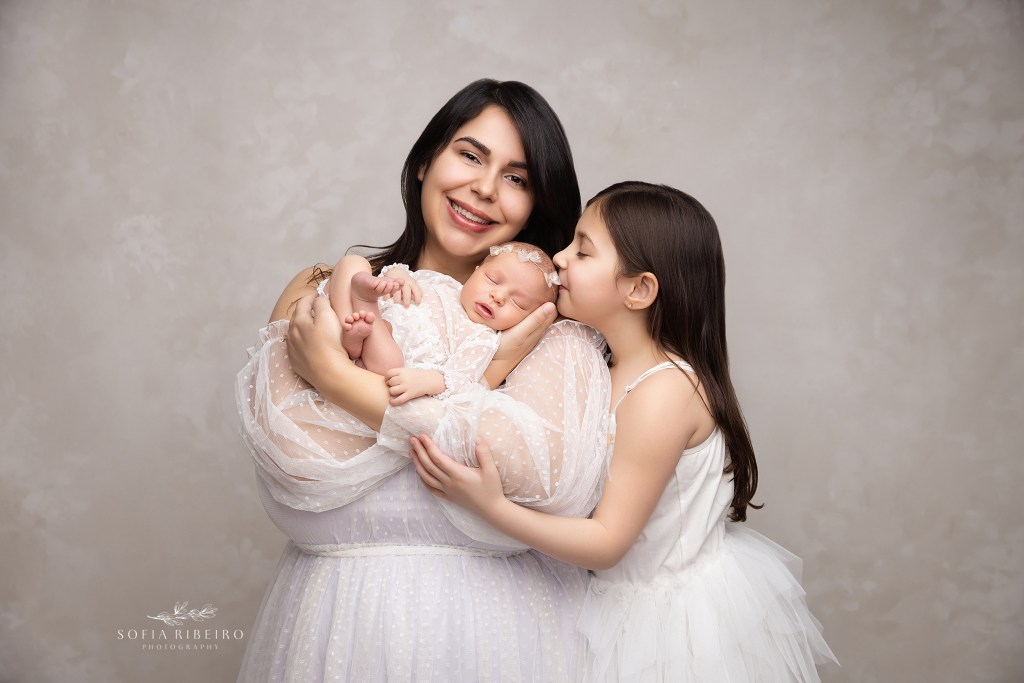 mom and big sister cradle their new little baby for a soft portrait in creams and whites in a dunellen nj newborn photographer's portrait studio