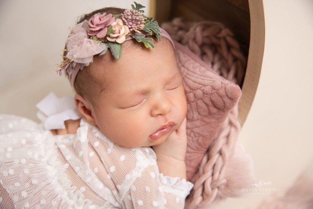 a closeup of this sweet baby girl's face, in pink and white toned props