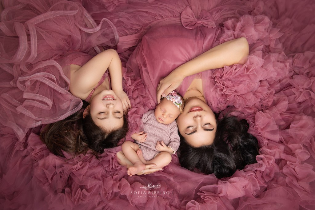 dunellen nj newborn photographer captures a portrait of mom with her baby girls nestled in pink ruffles