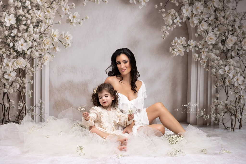 mom poses with daughter amidst some tulle and baby's breath for mother and daughter portraits in nj