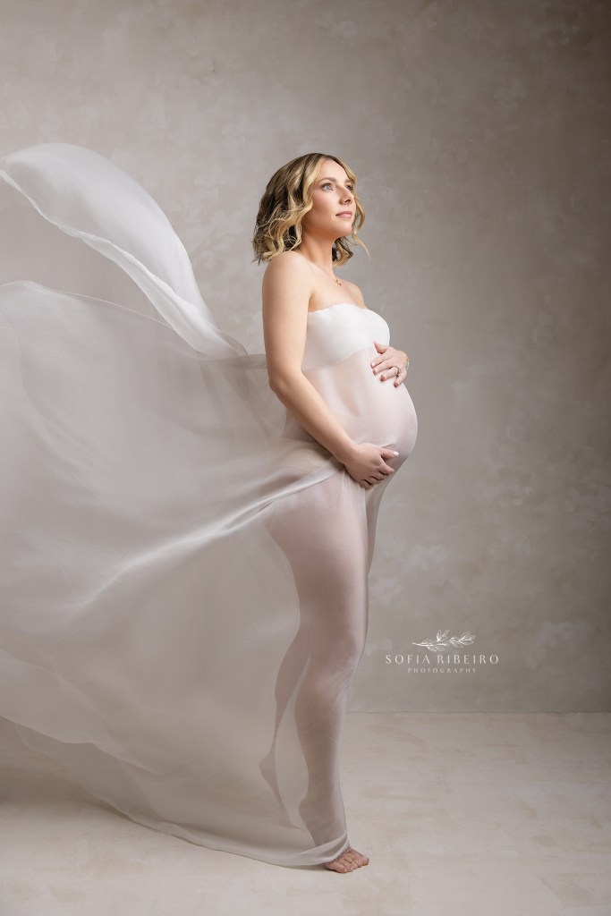 simple, flowing white fabric enhances mom's curves and baby bump in a side lit image in a maternity portrait studio in weehawken nj