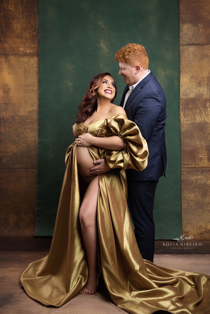 xpectant mom and dad pose together against a green and gold backdrop by a whippany nj maternity photographer