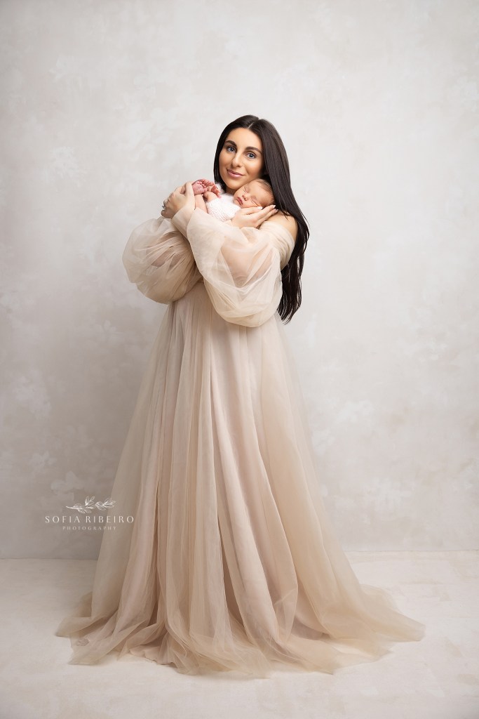 mom poses in elegant cream colors with her new baby boy