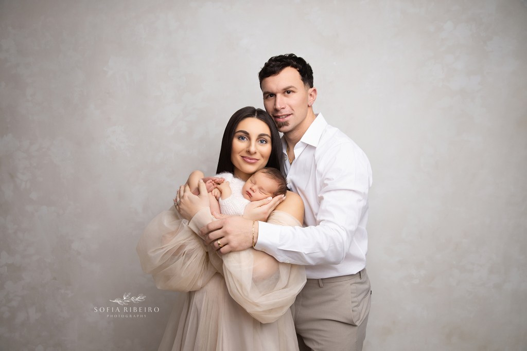 a new portrait of a growing family in neutral colors against a cream backdrop taken in a berkeley heights nj newborn photographer's studio