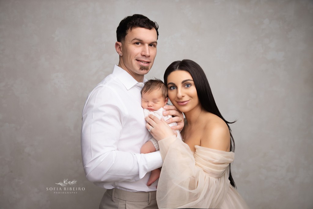 a new portrait of a growing family in neutral colors against a cream backdrop