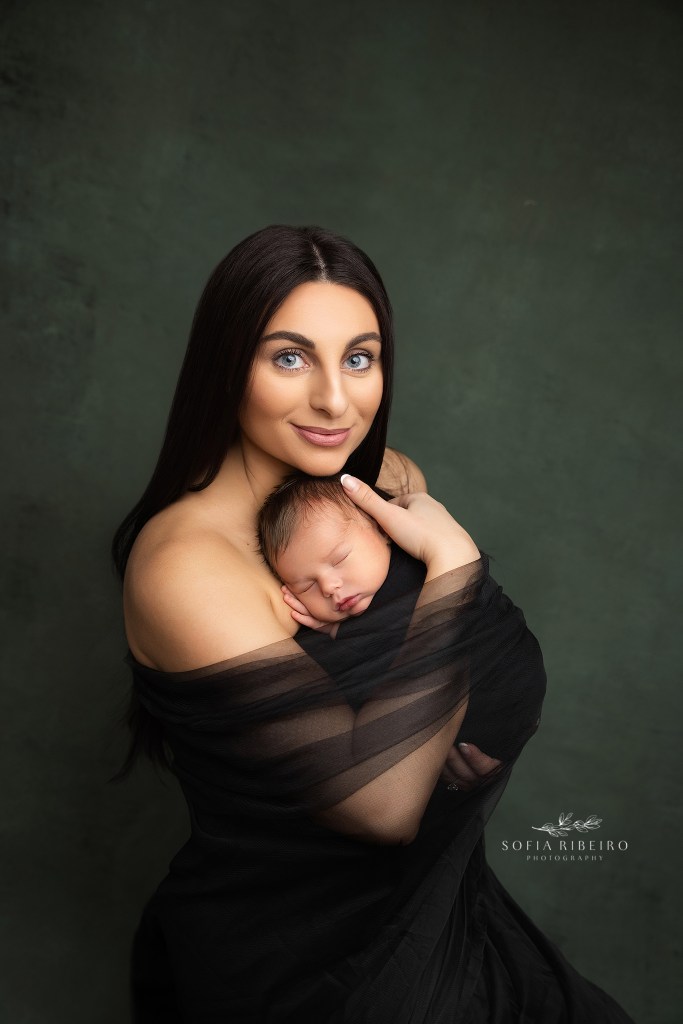 an intimate portrait of mom and baby wrapped in black tulle against a green backdrop with her newborn baby boy posed by berkeley heights nj newborn photographer