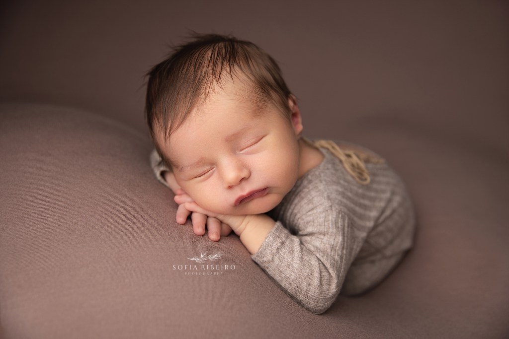 berkeley heights nj newborn photographer poses a baby boy in a sleepy position against a neutral backdrop