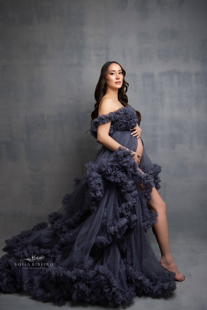 mom poses gracefully in a dark grey ruffled maternity gown
