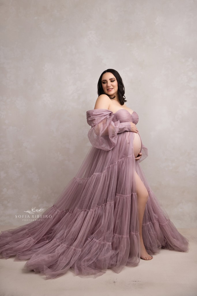 mom lovingly cradles her baby bump in a lavender maternity gown during a maternity session in hudson valley ny