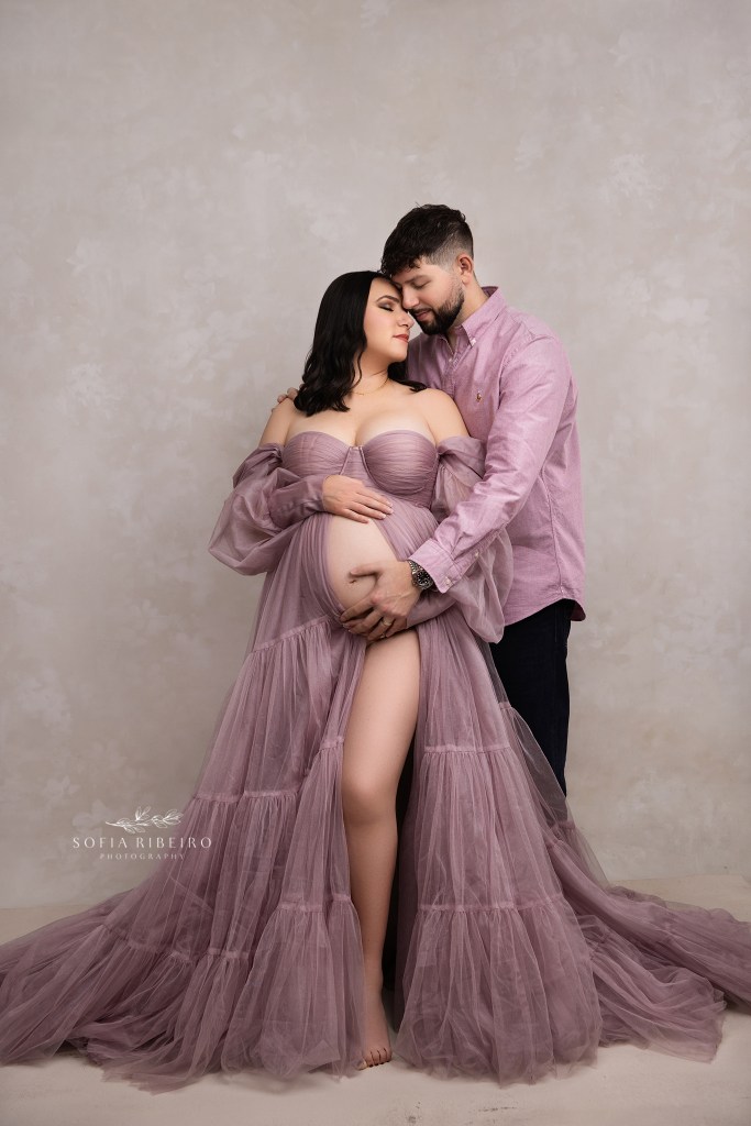 mom to be poses in a lavender tulle gown, with dad cradling her baby bump