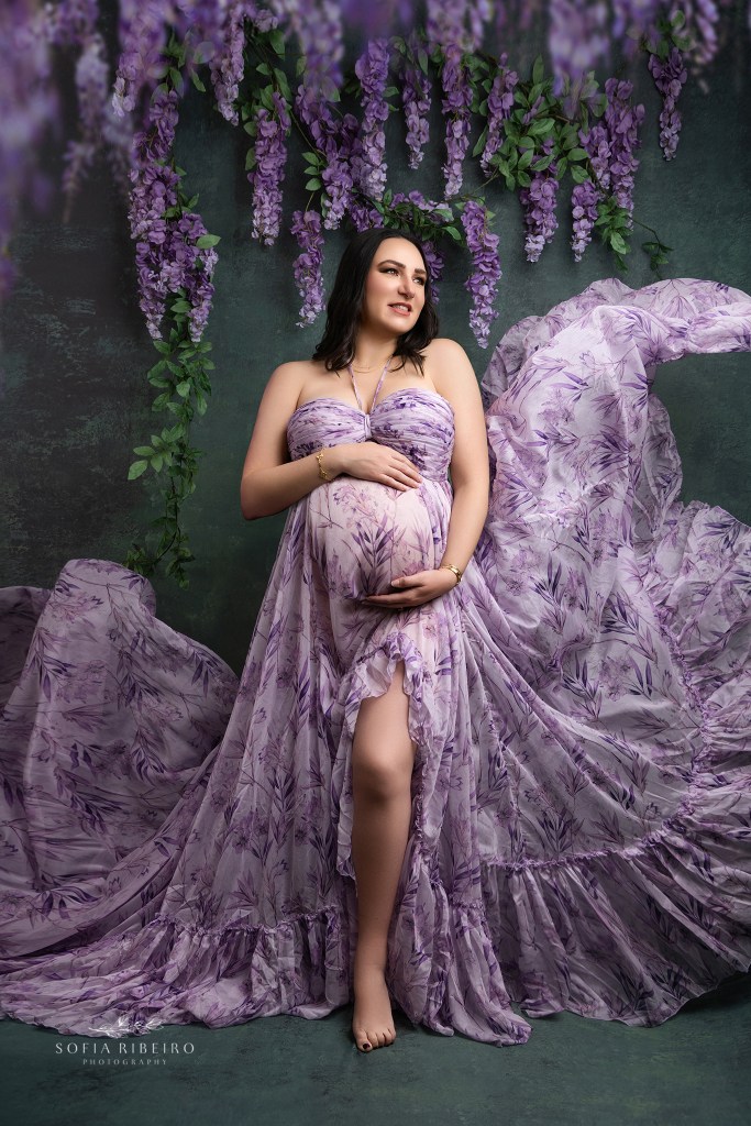 a flowing floral purple gown frames mom to be during a portrait session for maternity photos in hudson valley NY