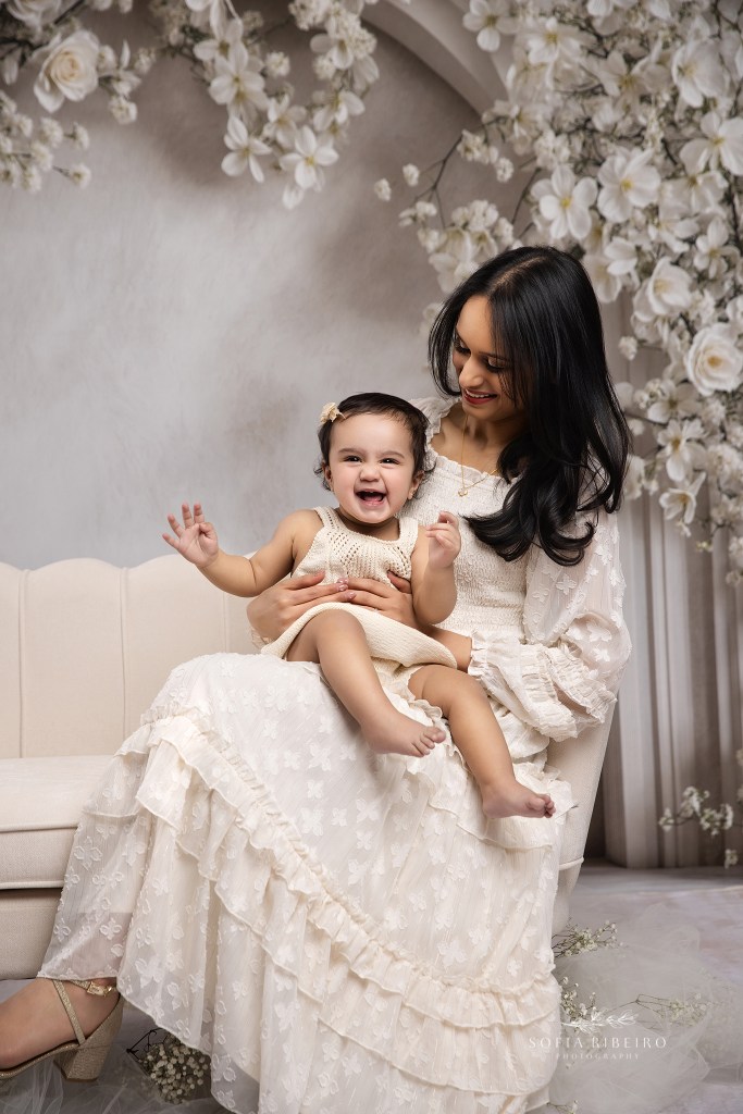 staten island ny family photographer captures a sweet portrait of mom and baby snuggled together on a sofa against a floral backdrop