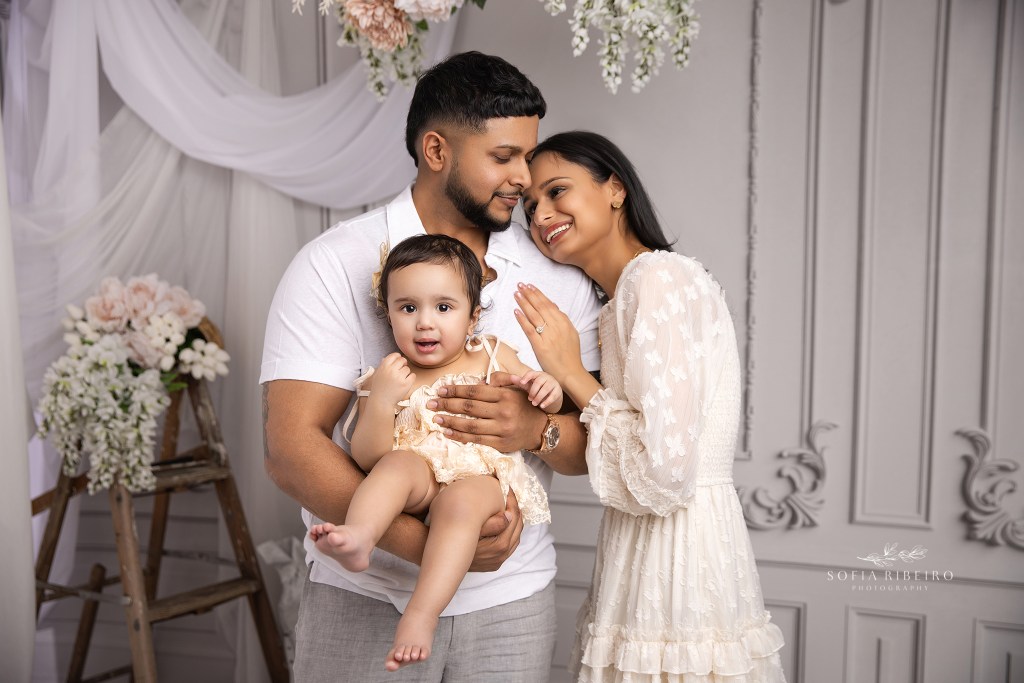 mom and dad share a sweet moment with their baby girl for family photos