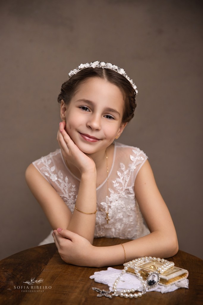 a westfield nj communino photographer captures a smiling portrait of a little girl in her communion dress showing beaded detail and hairpiece.