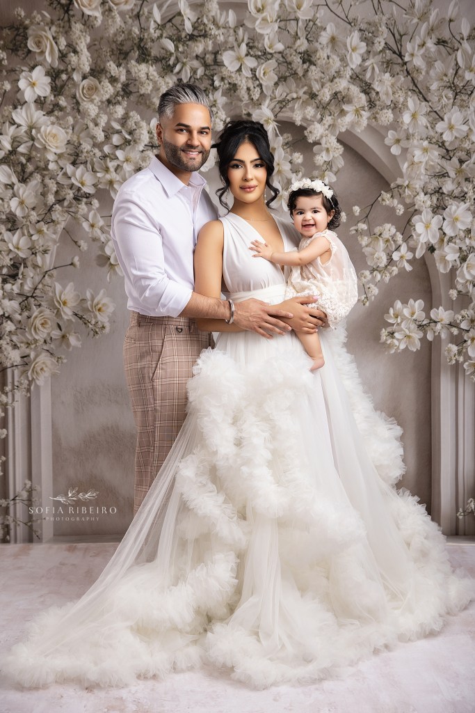 an edison nj family photographer captures an all white portrait of a glowing trio of mom, dad, and sweet baby girl