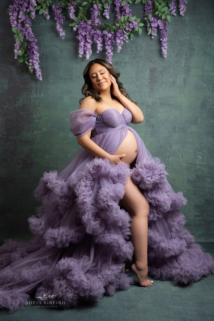 a ruffled lavender gown is opene to expose mom's growing baby bump against a teal backdrop in englewood nj photography studio
