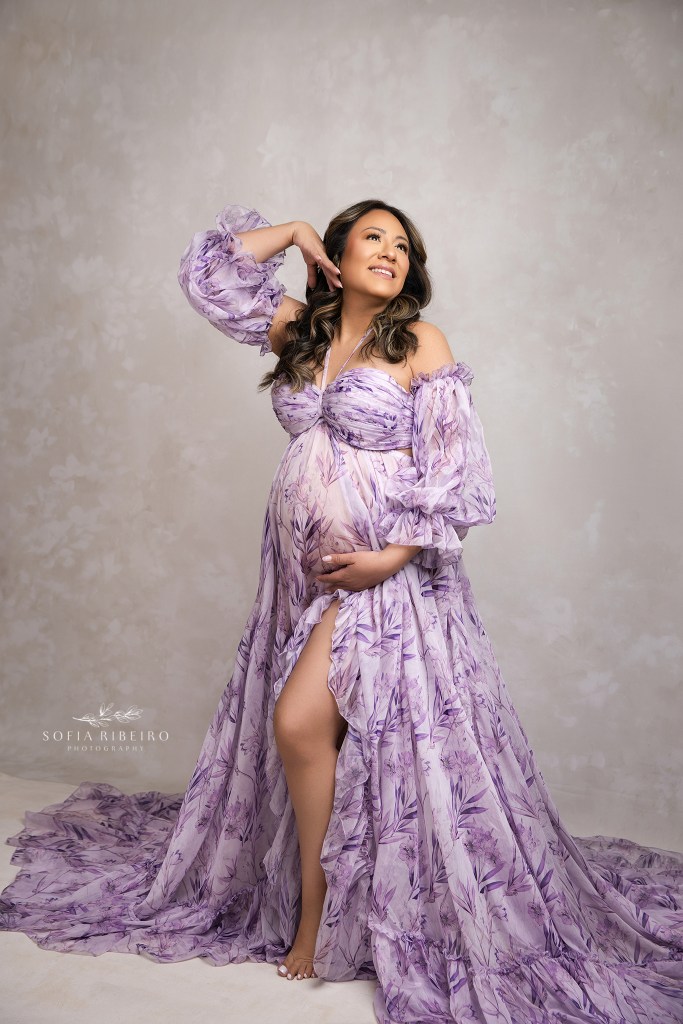 a purple floral dres is draped around moms belly in a striking maternity portrait by an englewood nj maternity photographer