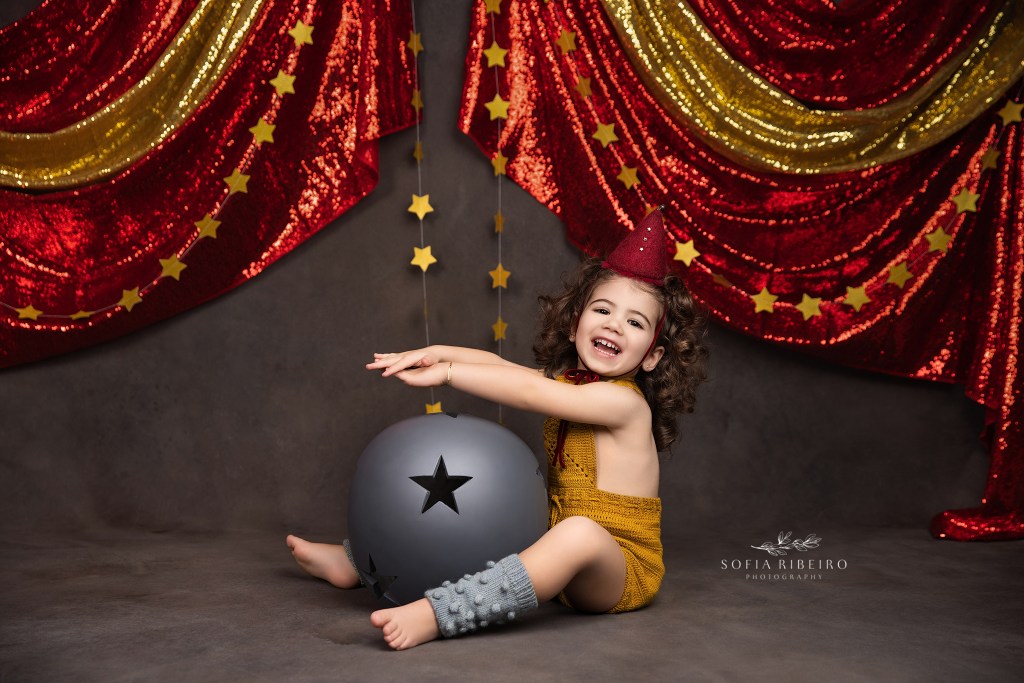 a little girl poses with a circus ball and hat for birthday images near red bank nj