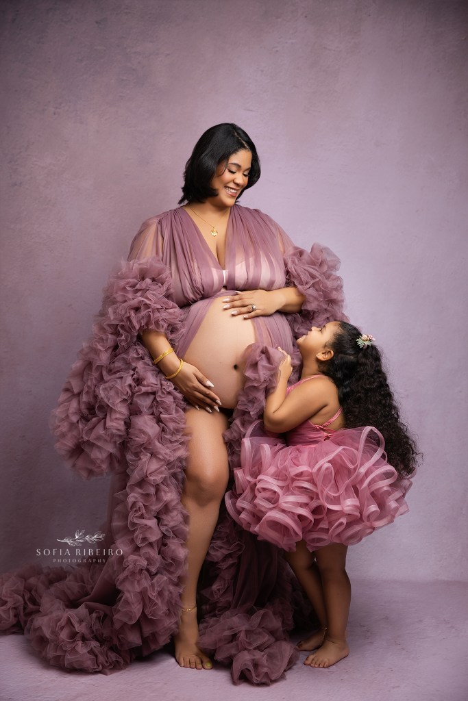 mom and older daughter share a sweet moment during her maternity portraits in mauve tones gowns