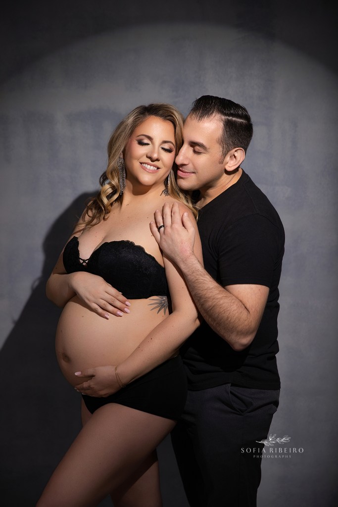 a maternity photographer in middletown nj captures a portrait of mom and dad to be in black matching outfits