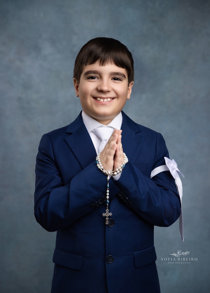 a boy smiles with rosary in hand for first communion portraits in clark nj