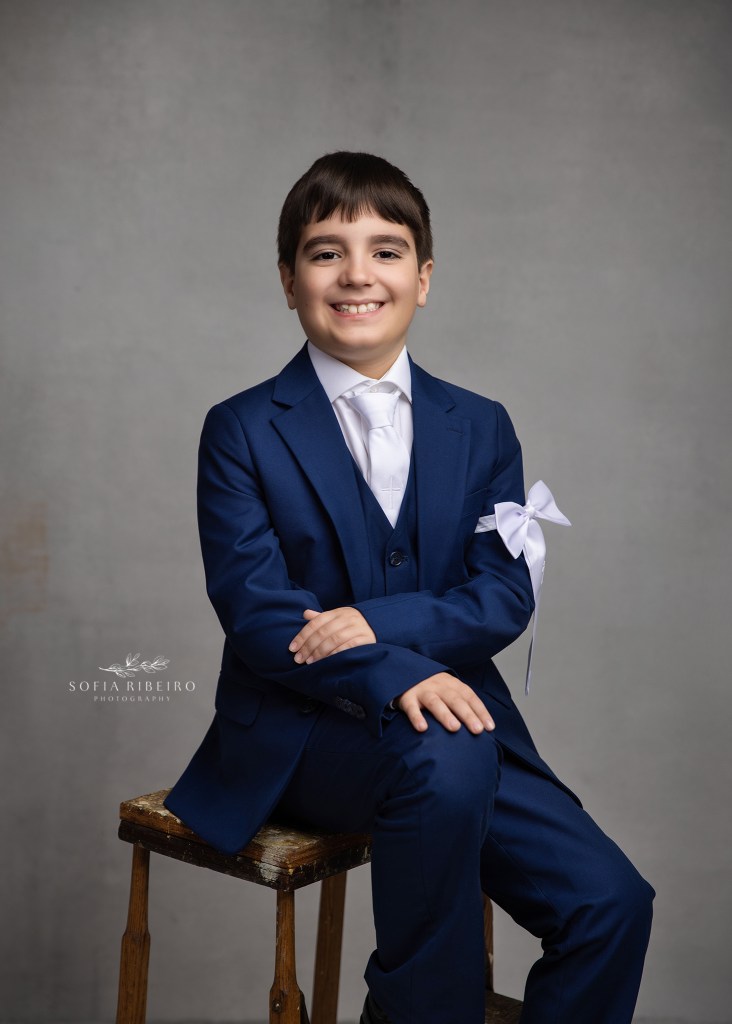 a clark nj communion photographer captures a young boy in his first communion navy suit against a grey backdrop