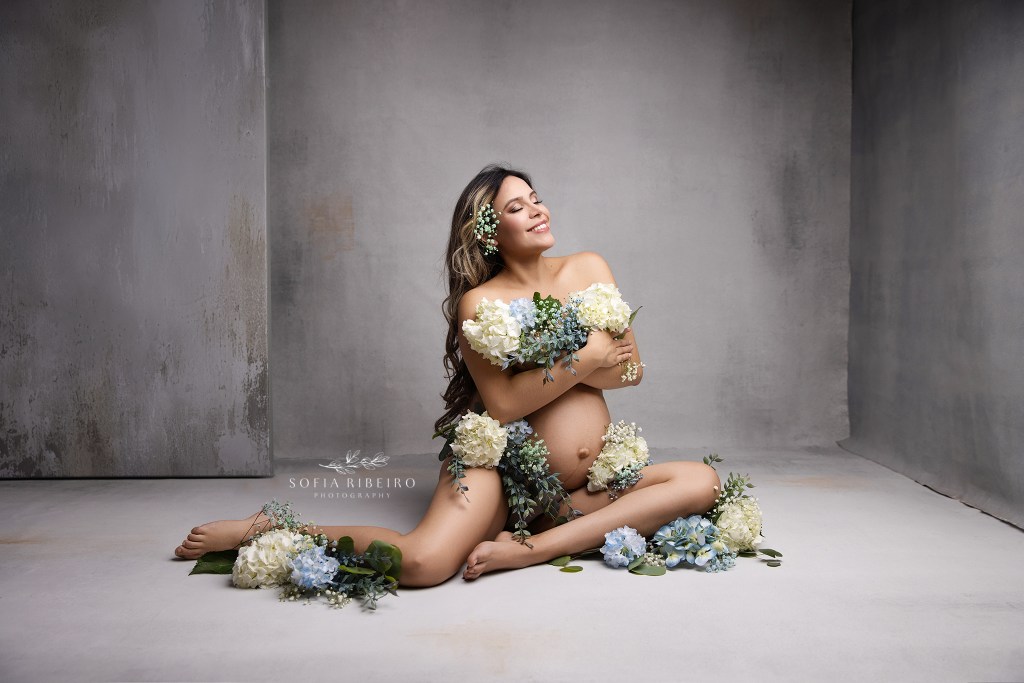 mom to be poses with an armload of soft blooms for a maternity portrait in glen ridge nj